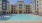 The pool area at our apartments in Allen, featuring beach chairs, and an outdoor lounge with couches and a TV.