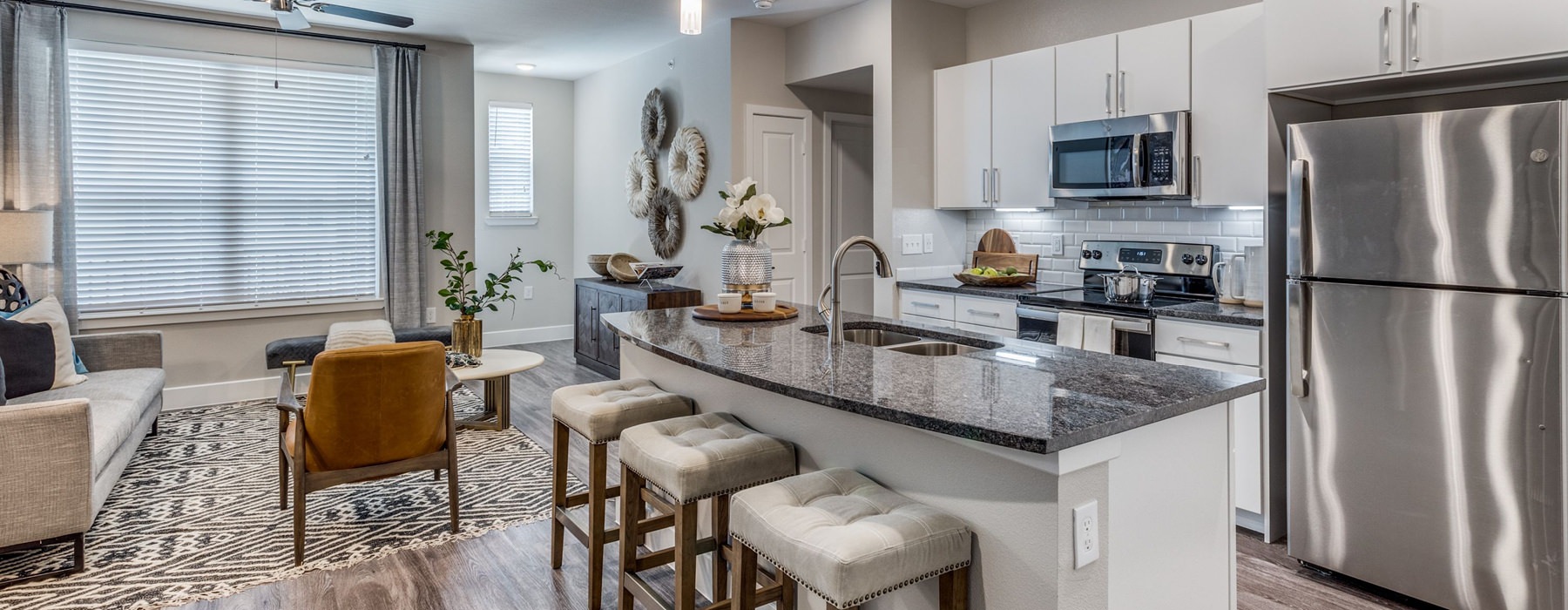Living room and kitchen at our apartments in Allen, TX, featuring granite countertops and stainless steel appliances.